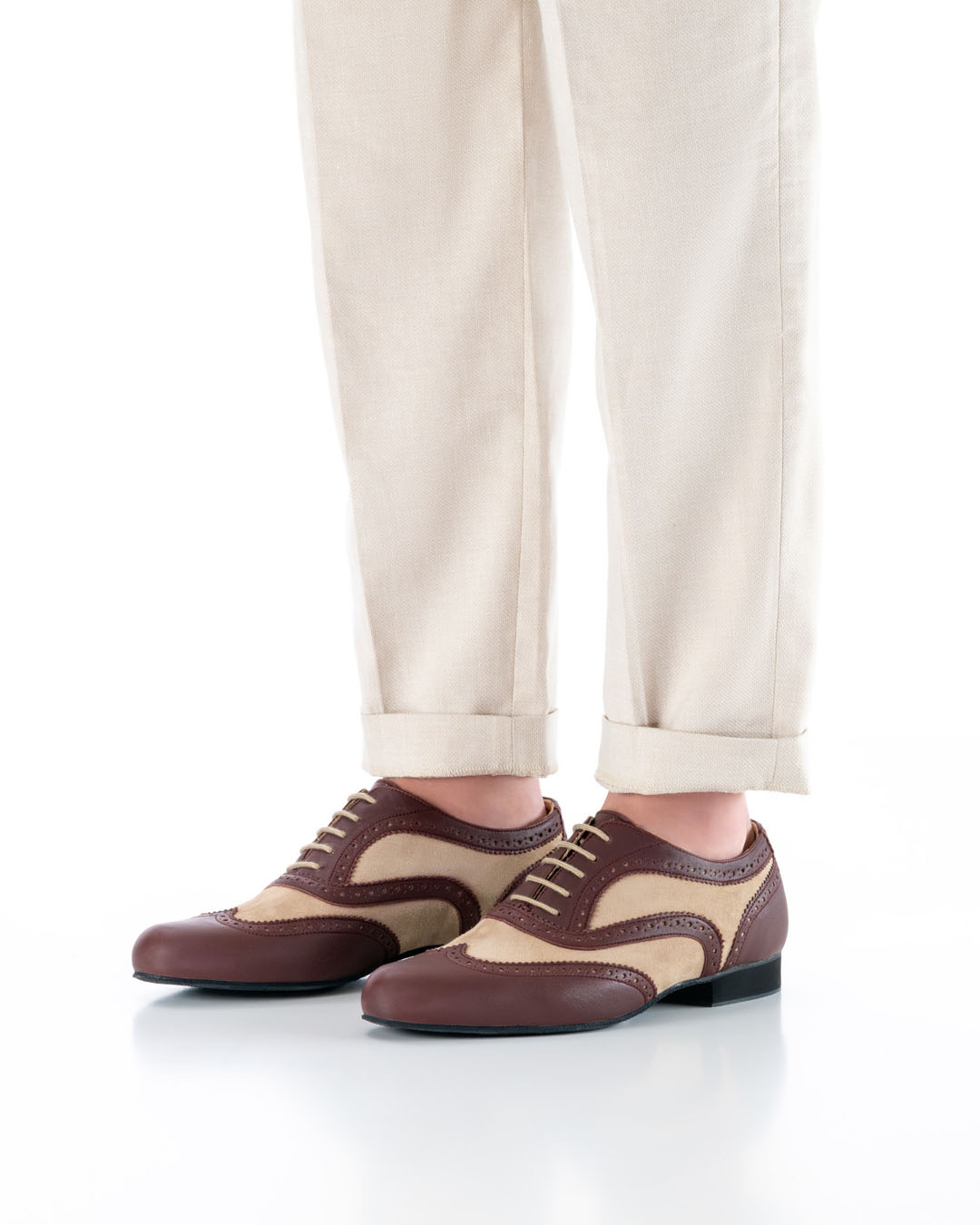 Model steht parallel mit beiden Füßen und heller Hose schräg diagonal zur Kamera und trägt elegante Tanzschuhe in beige-bordeaux farbenem Leder und Brogue Lochmuster mit hellen Schnürsenkeln