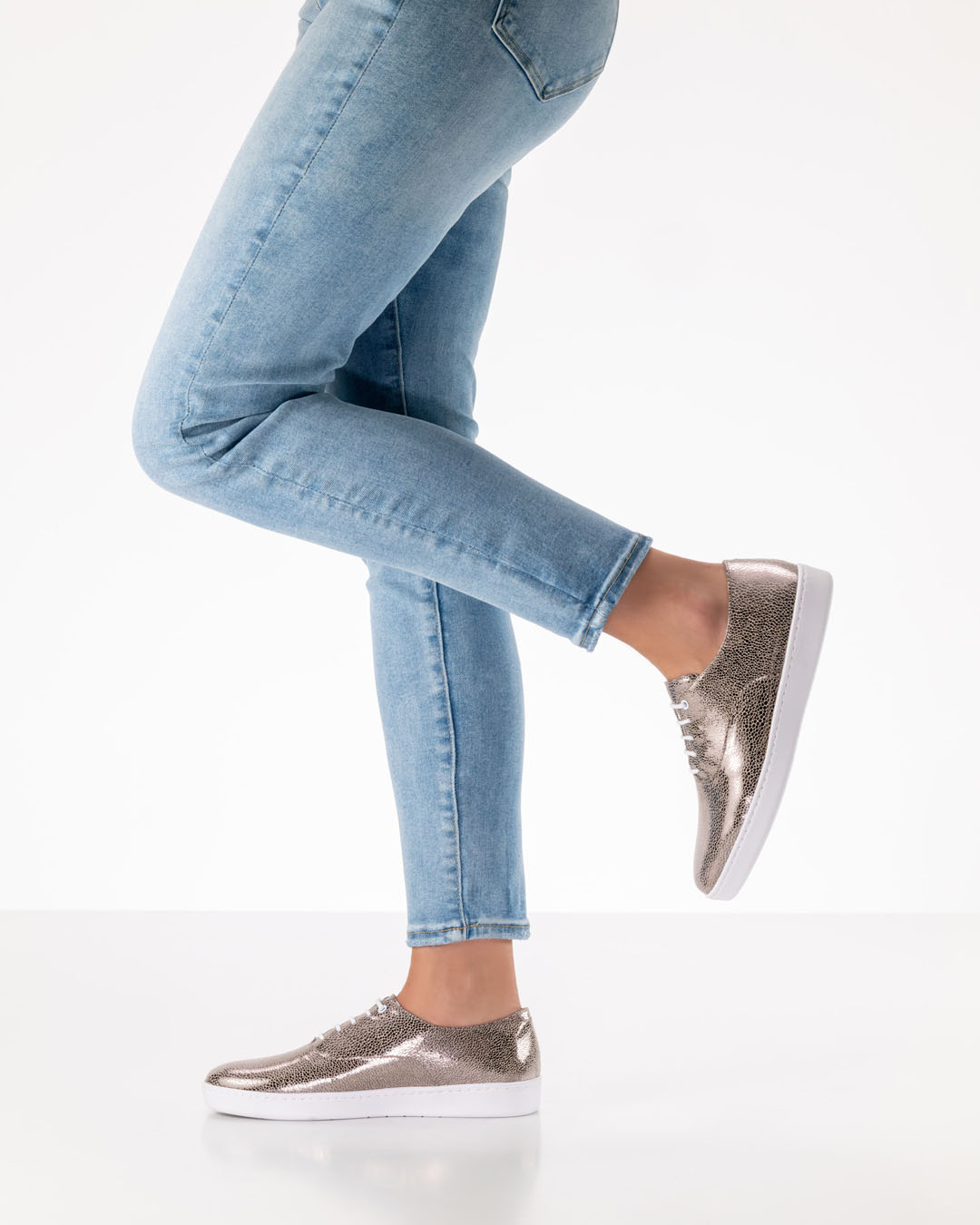 Beine eines Tanzschuhmodells in hellen Jeans mit platinfarbenen Tanzschuhen zum schnüren mit weißer Pu-Sohle 