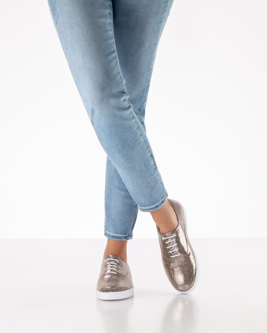 Platinfarbene, glänzende Tanzschuhe zum Schnüren mit weißer Sohle von Werner Kern getragen mit hellen Jeans