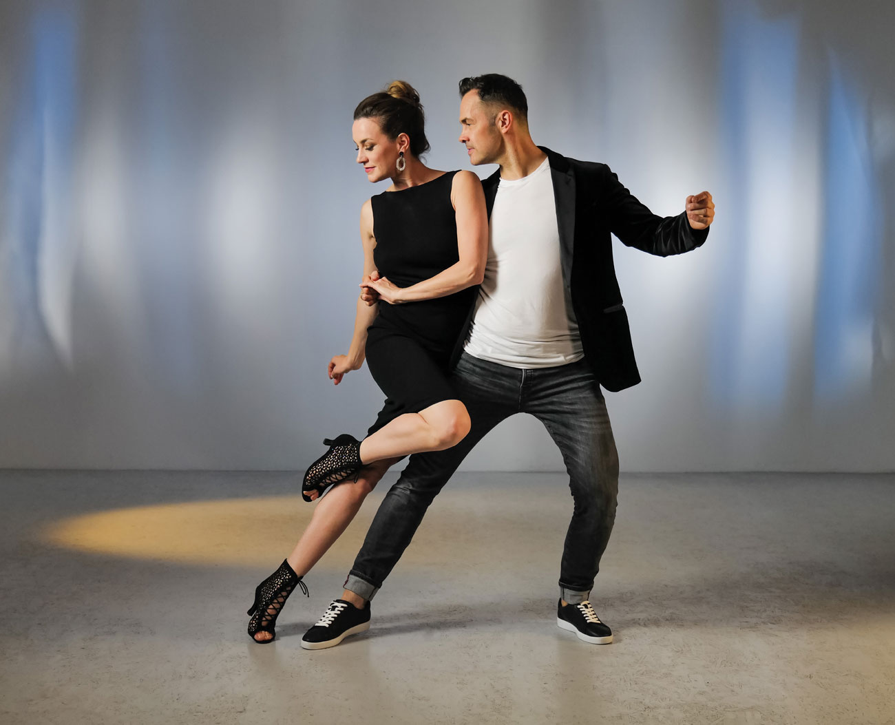 Junges Tanzpaar in Salsatanzpose mit schwarzen Tanzstiefelette und Tanzsneaker von Anna Kern