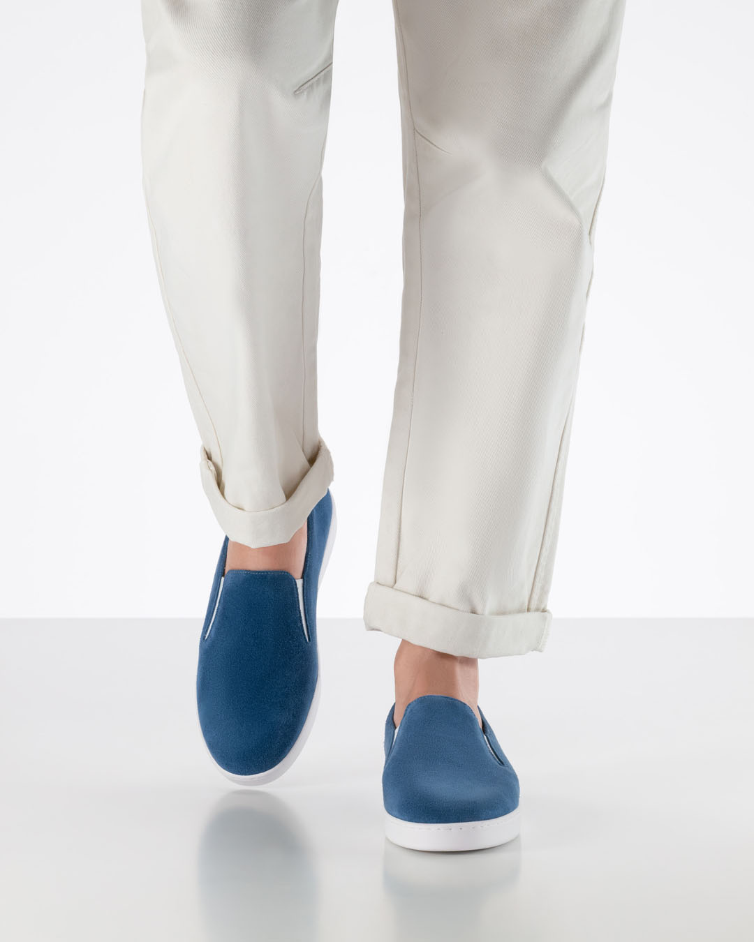 Modell läuft auf Kamera zu in weißer Hose und blauen Tanzsneakern aus Velourleder mit weißer Sohle