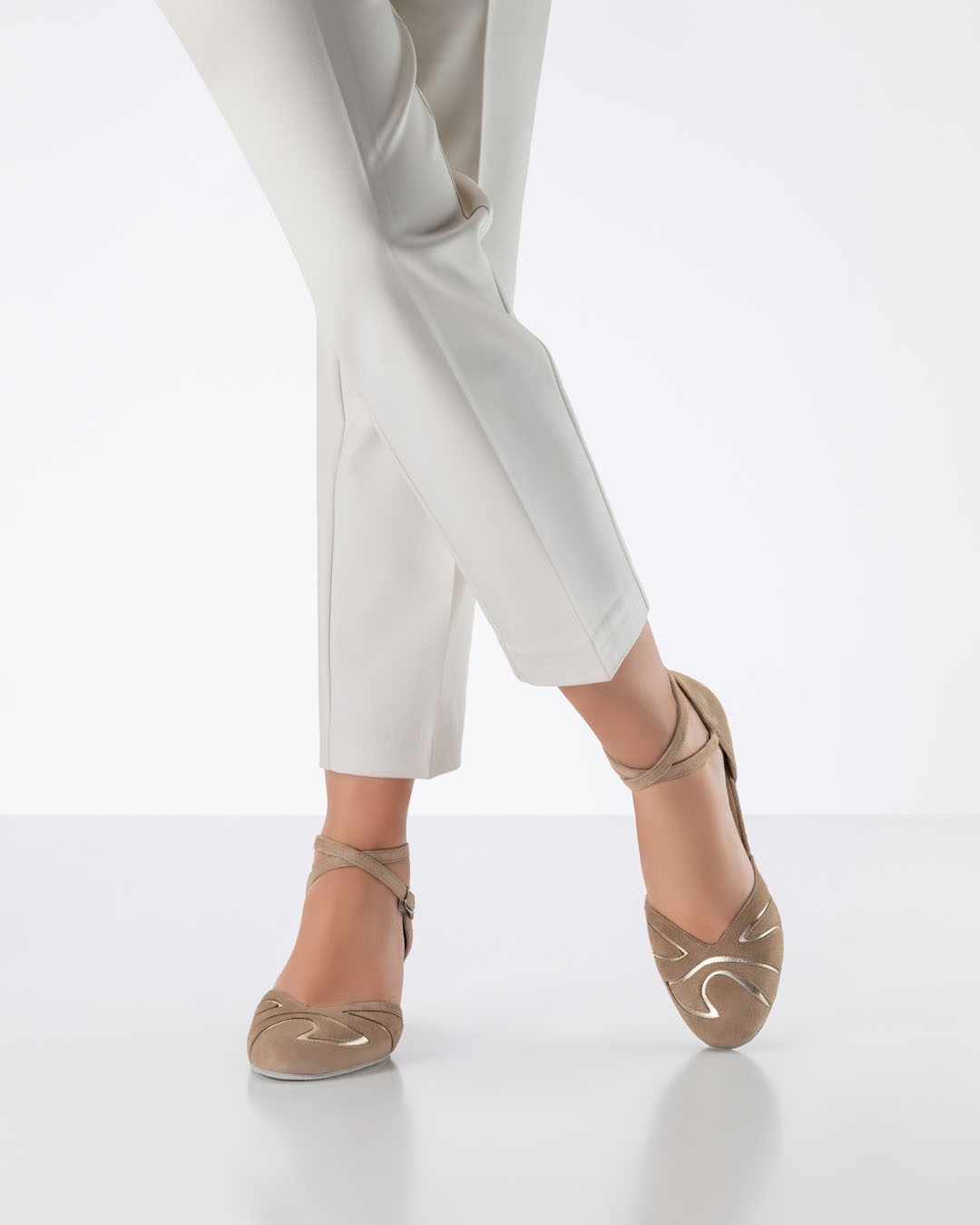 Model in hellbeiger Hose überkreuzt die Beine und trägt beige, geschlossene Tanzschuhe von Werner Kern