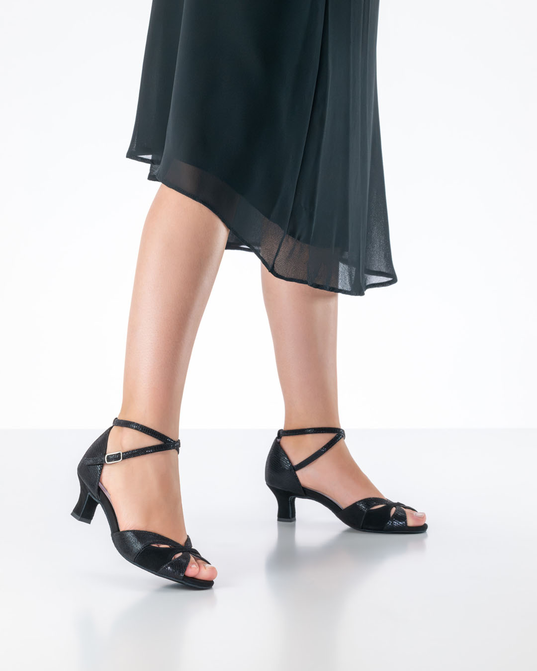 Model mit schwarzem Chiffonkleid präsentiert schwarze Tanzsandale Eunice mit 5 cm Flarabsatz von Anna Kern