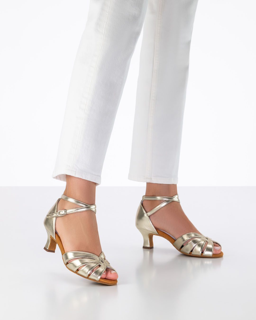 Modell trägt weiße Jeans und goldene Tanzsandalen mit 5 cm Flareabsatz 