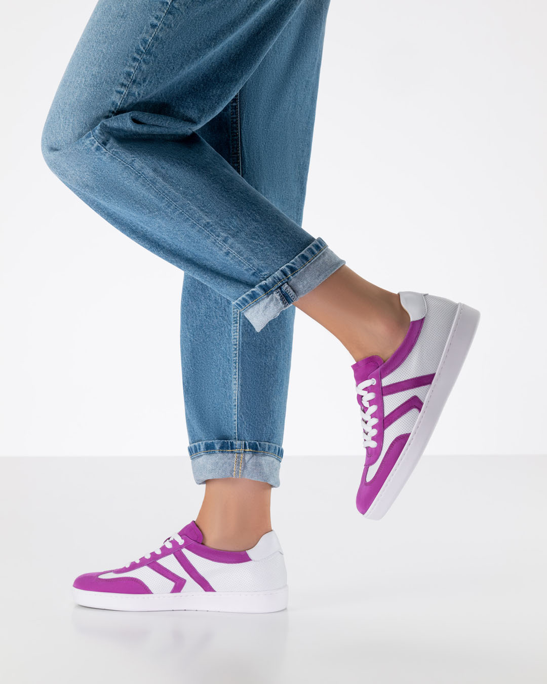 Modell mit lockeren Jeans und Tanzsneakern aus weißem Leder mit pinken Einsätzen