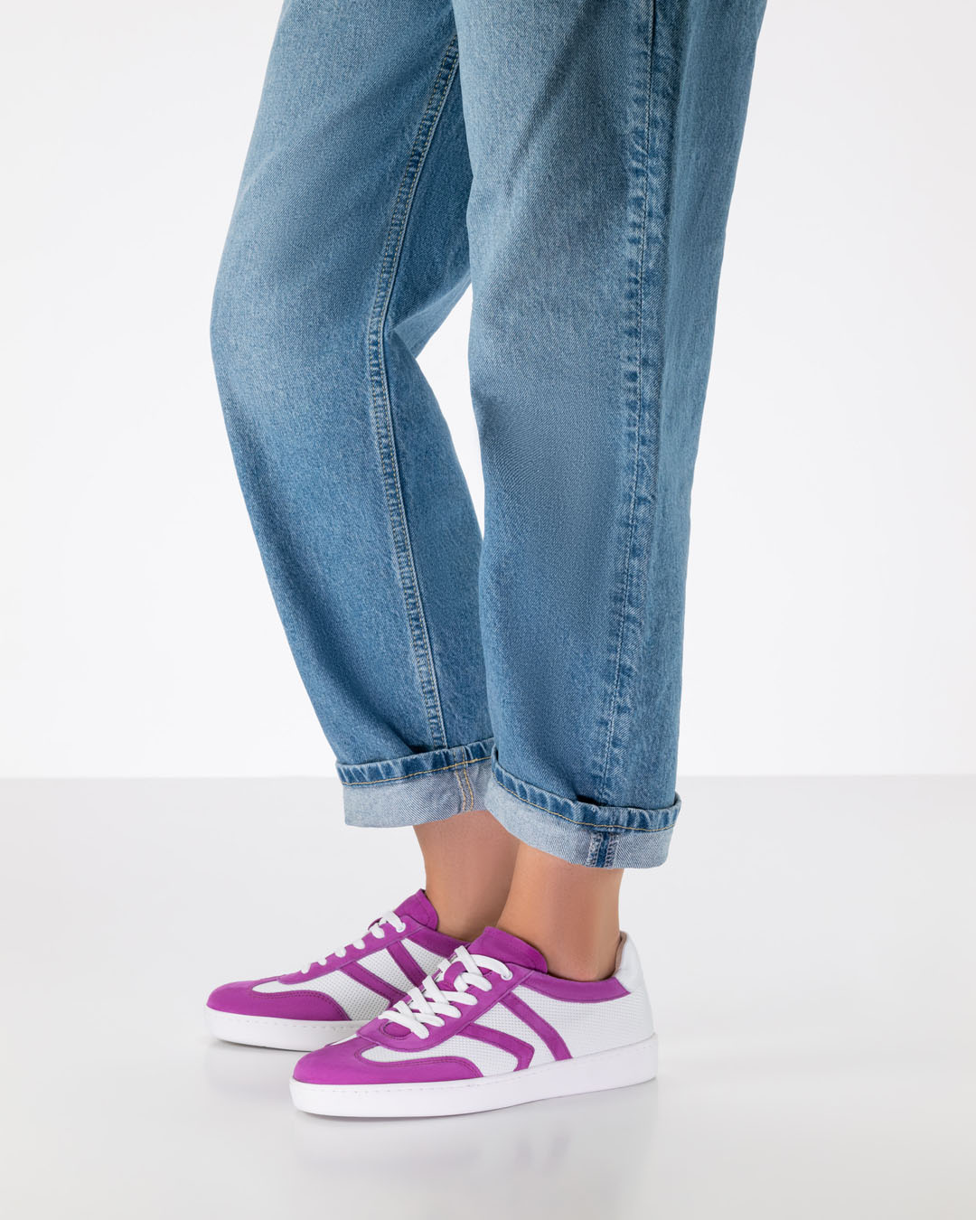 Beine eines Tanzschuhmodells in lässig geschnittenen Jeans und Tanzsneakern aus weiß-pinkem Leder mit weißer PU-Sohle